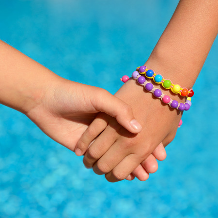 children hands over blue water outdoor, summer kids vacation conceptの写真素材