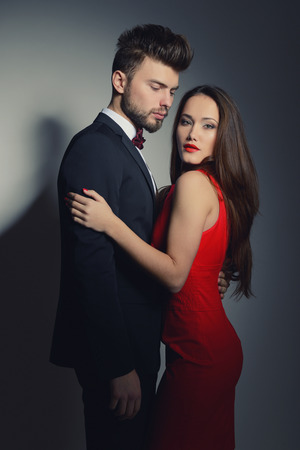 Sexy passion couple in love. Portrait of beautiful young man and woman dressed in classic clothes, studio shot over grey background の写真素材
