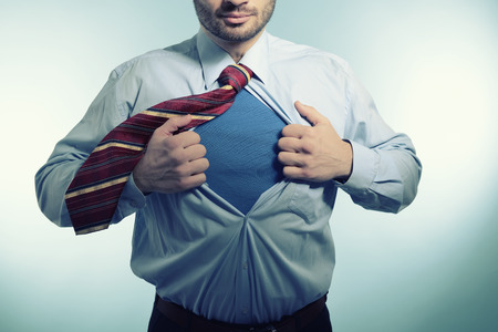 Business man opening his shirt like a superhero, over blue backgroundの写真素材