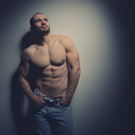 Strong athletic man with perfect body posing in studio on black background, tonedの写真素材
