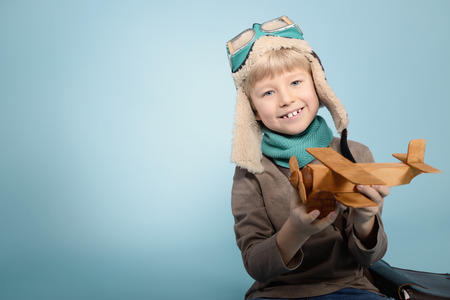 Little boy aviator dreaming and playing with wooden handmade toy plane, vintage tonedの写真素材