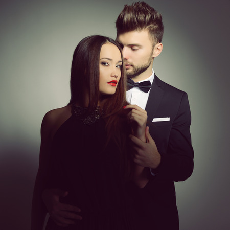Sexy passion couple in love. Portrait of beautiful young man and woman dressed in classic clothes, studio shot over grey background の写真素材