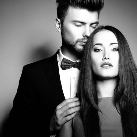 Sexy passion couple in love. Portrait of beautiful young man and woman dressed in classic clothes, studio shot over grey background の写真素材