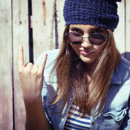 portrait of beautiful cool girl gesturing in hat and sunglasses, tonedの写真素材