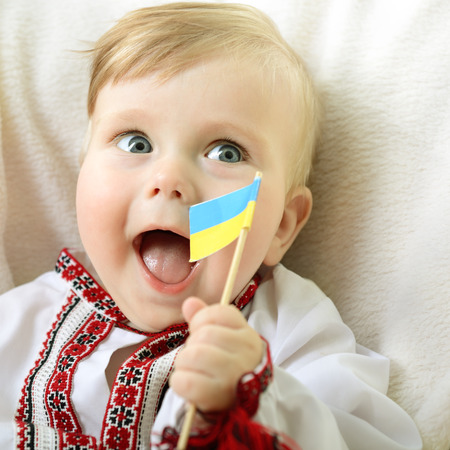 portrait of cute baby boy in national costume plaing with ucrainian flagの写真素材