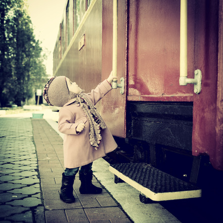 Little cute girl ready to vacation on railway station, baby girl fashion model go on travels, tonedの写真素材