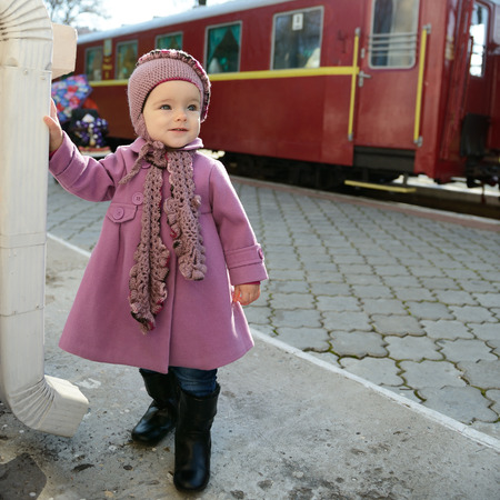 Little cute girl ready to vacation on railway station, baby girl fashion model go on travelsの写真素材