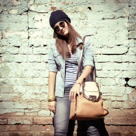 beautiful cool girl in hat and sunglasses against grunge wall, tonedの写真素材