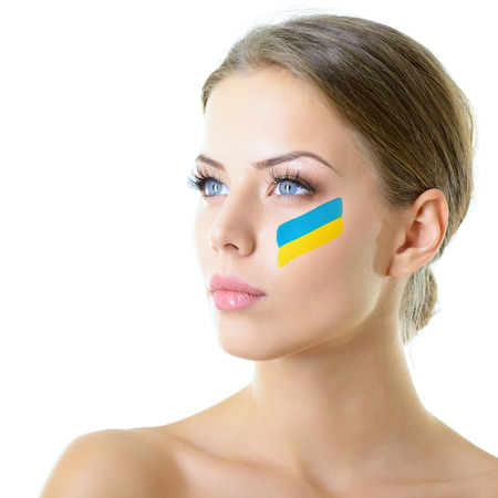 Portrait of attractive girl with ukrainian flag on her face, over on white background. Patriotism, independence, revolution in Ukraine.の写真素材