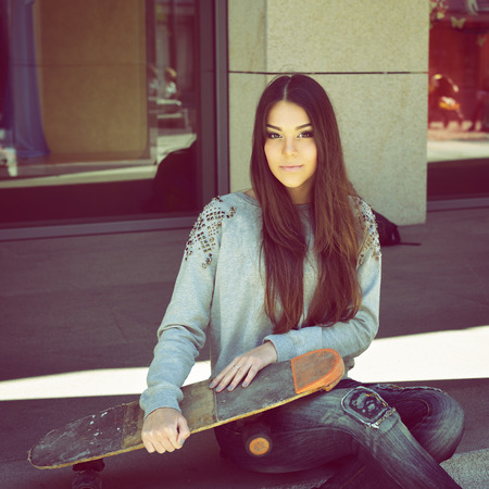 Beautiful teen girl with skateboard. Urban outdoors, teenager's lifestyle, toned.の写真素材