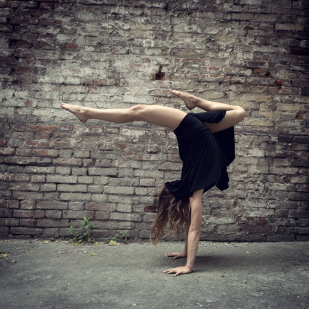 Attractive teen girl dancing outdoor against grunge brics wall. Toned.の写真素材