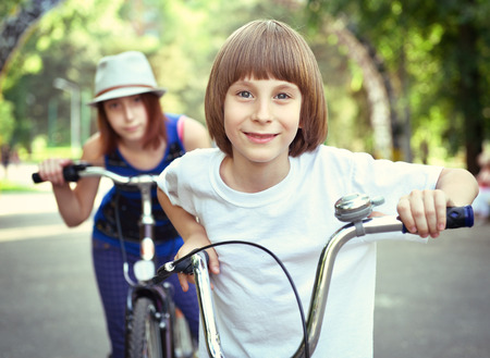 Two children with bicycles bike in park. Childhood, happiness, active kids lifestyle. Toned.の写真素材