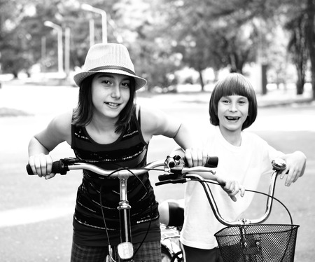 Two children with bicycles bike in park. Childhood, happiness, active kids lifestyle. Black and white.の写真素材