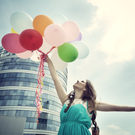 Happy romantic fashion girl with colorful balloons, outdoors. Toned.の写真素材