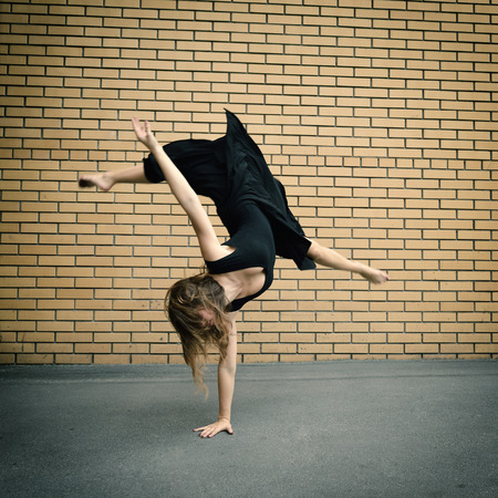 Attractive teen girl dancing outdoor against brics wall. Toned.の写真素材