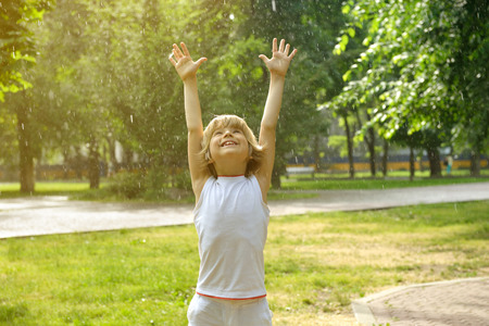 Little boy has fun in the summer rain, tonedの写真素材