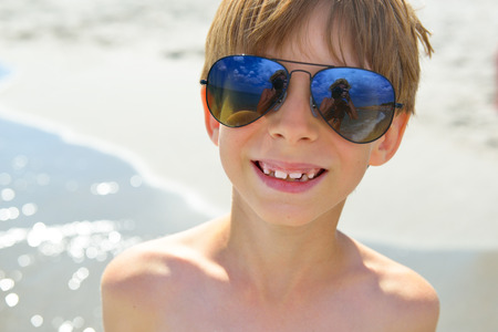 Portrait of happy child boy with big sunglasses on the beach.の写真素材