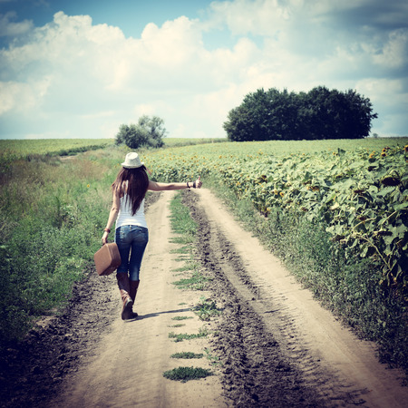 young woman with retro suitcase traveling in countryside, summer nature outdoor, tonedの写真素材