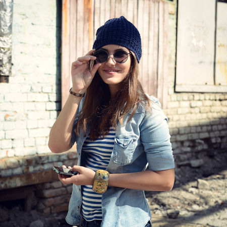 Pretty young woman using mobile phone and getting photos, outdoor. Toned.の写真素材