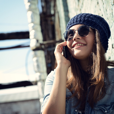 Girl having fun outdoors calling smart phone, lifestyle. Toned.の写真素材