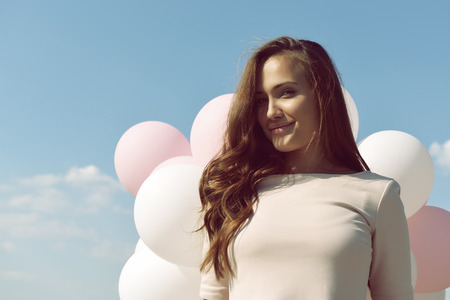 Fashion girl with  air balloons over blue sky, image toned.の写真素材