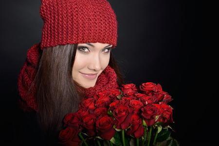 Beautiful Woman with Fresh Red Roses. Girl and Flowers over Black Background. Beauty Female Face. Happiness, Freshness, Beauty, Youth.の写真素材