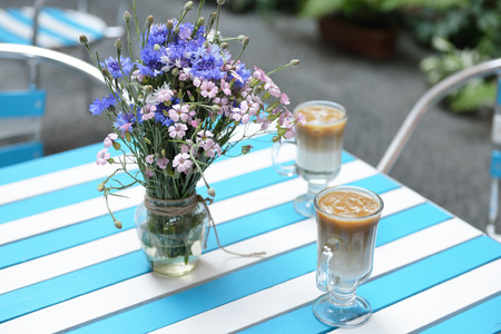 table with fresh wild flowers and ice coffee