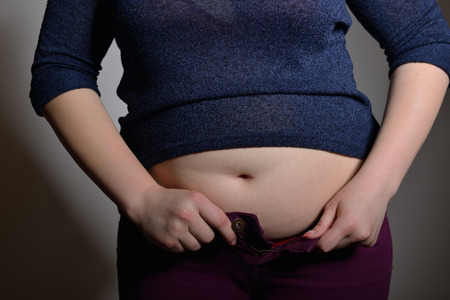Obese woman trying to close the buttons of her jeansの写真素材