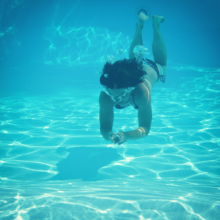 woman swimming underwater in pool, image tonedの写真素材