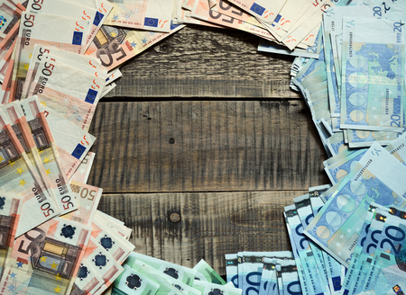 Round frame of euro banknotes. Background with european cash money on wooden background. Image toned.の写真素材