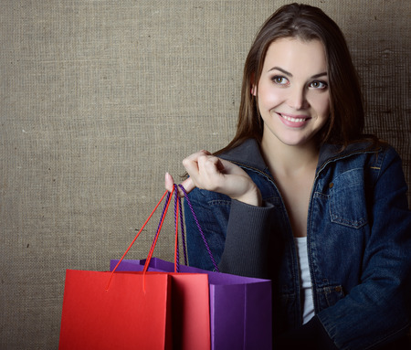 Young happy smiling woman holding red and purple shopping bags over canvas, image toned.の写真素材