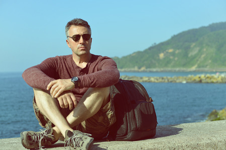 Handsome man over sea view. Outdoor male portrait. Trip, vacation, holiday, tourism, leisure, lifestile, summer time concept, image toned.の写真素材
