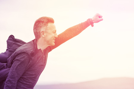 Superhero flying over sky and mountain landscape over sunrise. Success, power, faith in e
your strenght, leadership and victory concept. Hero is among us. Image toned.の写真素材