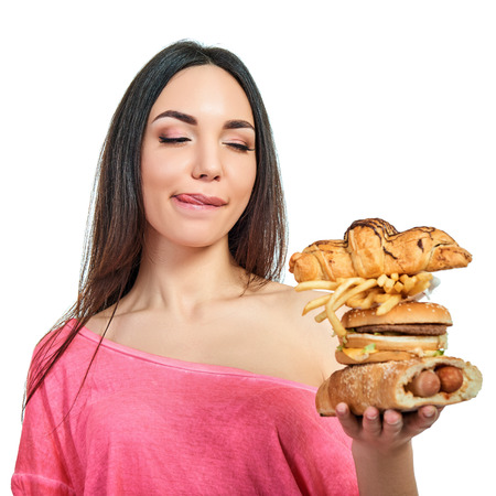 Young woman with fast food. Girl eating hamburger and fries over white background. Unhealthy eating.の写真素材