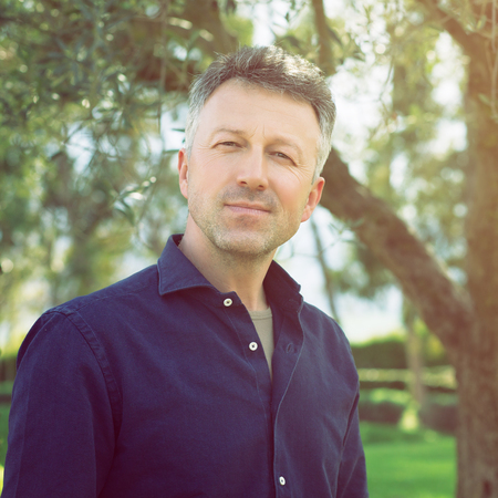 Man in olive grove, image toned. Portrait of handsome mature man lokking at camera over nature...