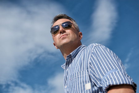 Handsome man. Outdoor male portrait. Middle-aged man, summer outdoor portrait over sky, image toned.の写真素材