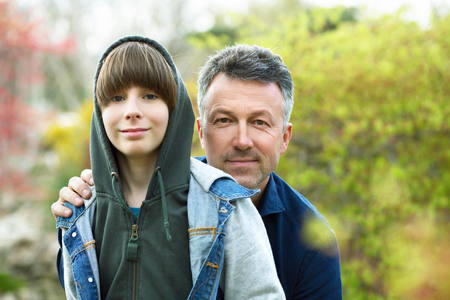 Father with son outdoors portrait. Mid adult father and his 11 years son posing over spring outdoor.の写真素材
