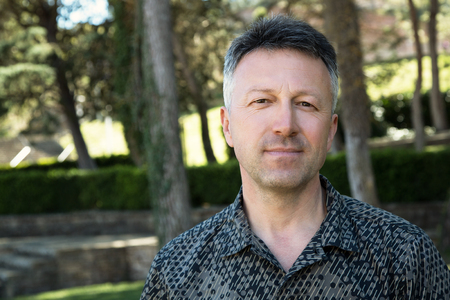 Outdoor male portrait. Mid adult man looking at camera over spring park outdoorの写真素材