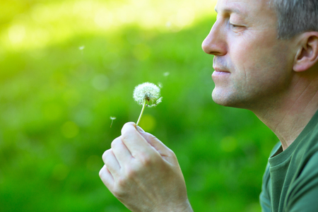 Man with dandelion over blured green grass, summer nature outdoorの写真素材