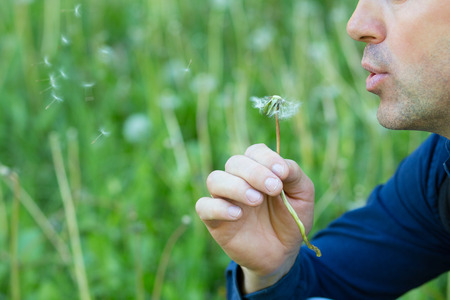 Man with dandelion over blured green grass, summer nature outdoorの写真素材