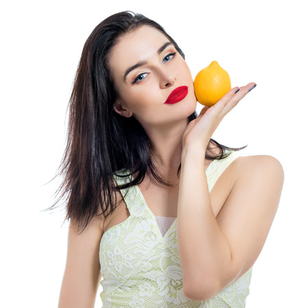 Excited beautiful girl holding lemon and posing in studio over white background.の写真素材