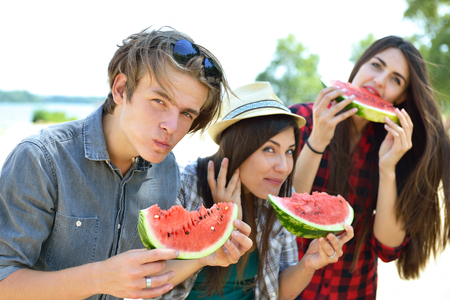 Happy friends eating watermelon on the beach.の写真素材