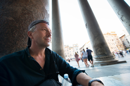 Handsome mid adult man sitting near column outside the Pantheon, Rome, Italy. Majestic Pantheon. Tourist in Italy. Roman vacation.の写真素材