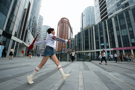 Beautiful smiling chinese young woman wearing traditional ukrainian clothes walking in center of Beijing city, China.の写真素材