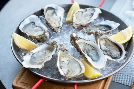 Fresh oysters with lemon's slices in ice. Restaurant delicacy. Saltwater oysters dish.の写真素材