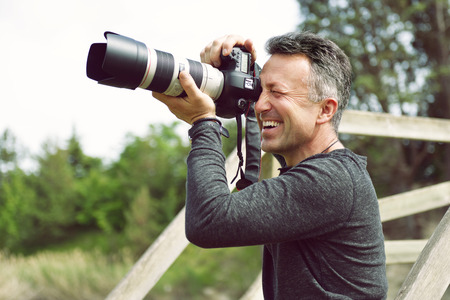 Man professional photographer with digital camera takes photos outdoor. Photo camera in male hands....