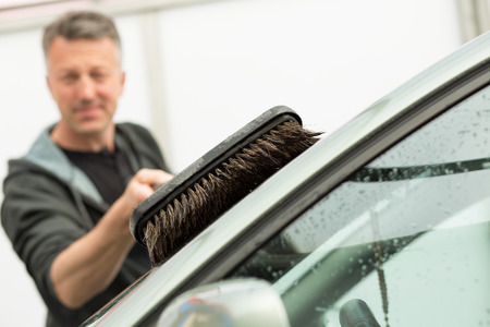 Car washing. Man cleaning car using high pressure water and brush outdoorの写真素材