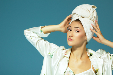 Cheerful attractive funny teen girl with towel on her head, over blue background. Morning beautiful young womanの写真素材