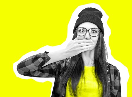 Excited surprised young woman covers hands open mouth over yellow background. Emotional female portrait. Modern high fashion lookの写真素材