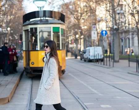 Attractive young woman wearing gray coat with long dark hair and sun glasses posing outdoor in Milan streets, Italy. Beautiful caucasian model portrait.の写真素材